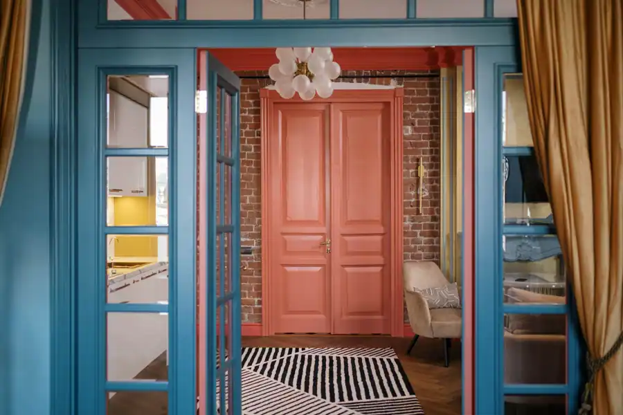 A stylish interior featuring bright blue and red doors with brick walls and modern decorations.