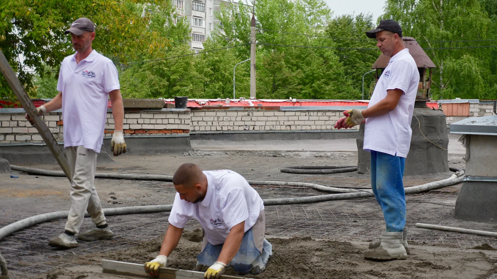 Team of construction workers pouring and leveling cement on a rooftop.