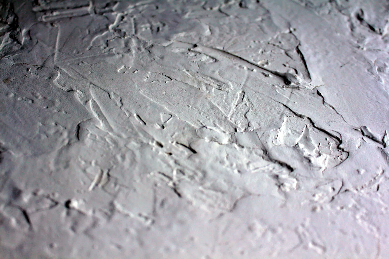 Close-up shot of a textured white plaster surface with rough details.